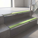 Mirroflect Silver mirror-finish aluminium stair nosing fitted along two concrete steps in an office stairwell, with an Apple Green anti-slip insert running the full width of each step