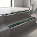 Mirroflect Silver mirror-finish aluminium stair nosing fitted along two concrete steps in an office stairwell, with a Dark Green anti-slip insert running the full width of each step