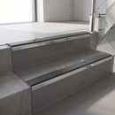 Mirroflect Silver mirror-finish aluminium stair nosing fitted along two concrete steps in an office stairwell, with a Dark Grey anti-slip insert running the full width of each step