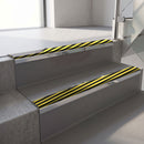 Mirroflect Silver mirror-finish aluminium stair nosing fitted along two concrete steps in an office stairwell, with a black and yellow Hazard anti-slip insert running the full width of each step