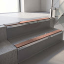 Mirroflect Silver mirror-finish aluminium stair nosing fitted along two concrete steps in an office stairwell, with a Mid Brown anti-slip insert running the full width of each step