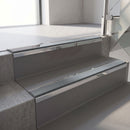 Mirroflect Silver mirror-finish aluminium stair nosing fitted along two concrete steps in an office stairwell, with a Mid Grey anti-slip insert running the full width of each step