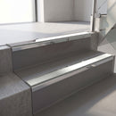 Mirroflect Silver mirror-finish aluminium stair nosing fitted along two concrete steps in an office stairwell, with an Oyster anti-slip insert running the full width of each step