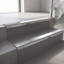 Mirroflect Silver mirror-finish aluminium stair nosing fitted along two concrete steps in an office stairwell, with a Polar Grey anti-slip insert running the full width of each step