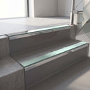 Mirroflect Silver mirror-finish aluminium stair nosing fitted along two concrete steps in an office stairwell, with a Sage Green anti-slip insert running the full width of each step