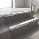 Mirroflect Silver mirror-finish aluminium stair nosing fitted along two concrete steps in an office stairwell, with a White anti-slip insert running the full width of each step