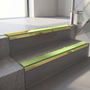 Mirrorflect Gold mirror-finish aluminium stair nosing fitted along two concrete steps in an office stairwell, with an Apple Green anti-slip insert running the full width of each step
