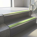Square-edge aluminium stair nosing fitted along two concrete steps in an office stairwell, with an Apple Green anti-slip insert running the full width of each step