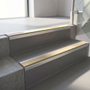Square-edge aluminium stair nosing fitted along two concrete steps in an office stairwell, with a Beige anti-slip insert running the full width of each step