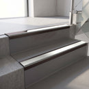 Dark Bronze aluminium stair nosing fitted along two concrete steps in an office stairwell, with an Oyster anti-slip insert running the full width of each step