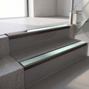 Dark Bronze aluminium stair nosing fitted along two concrete steps in an office stairwell, with a Sage Green anti-slip insert running the full width of each step