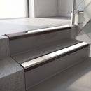 Dark Bronze aluminium stair nosing fitted along two concrete steps in an office stairwell, with a White anti-slip insert running the full width of each step