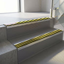 Square-edge aluminium stair nosing fitted along two concrete steps in an office stairwell, with a black and yellow Hazard anti-slip insert running the full width of each step