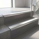 Square-edge aluminium stair nosing fitted along two concrete steps in an office stairwell, with an Oyster anti-slip insert running the full width of each step