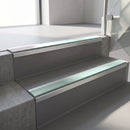 Square-edge aluminium stair nosing fitted along two concrete steps in an office stairwell, with a Sage Green anti-slip insert running the full width of each step