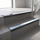 Satin Black aluminium stair nosing fitted along two concrete steps in an office stairwell, with an Aura anti-slip insert running the full width of each step