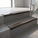 Satin Black aluminium stair nosing fitted along two concrete steps in an office stairwell, with a Brown anti-slip insert running the full width of each step