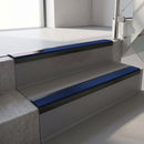 Satin Black aluminium stair nosing fitted along two concrete steps in an office stairwell, with a Dark Blue anti-slip insert running the full width of each step