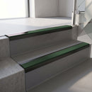 Satin Black aluminium stair nosing fitted along two concrete steps in an office stairwell, with a Dark Green anti-slip insert running the full width of each step