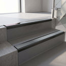 Satin Black aluminium stair nosing fitted along two concrete steps in an office stairwell, with a Mid Grey anti-slip insert running the full width of each step