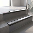Satin Black aluminium stair nosing fitted along two concrete steps in an office stairwell, with a Polar Grey anti-slip insert running the full width of each step