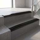 Satin Black aluminium stair nosing fitted along two concrete steps in an office stairwell, with a Premium Black anti-slip insert running the full width of each step