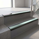 Satin Black aluminium stair nosing fitted along two concrete steps in an office stairwell, with a Sage Green anti-slip insert running the full width of each step