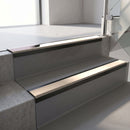 Satin Black aluminium stair nosing fitted along two concrete steps in an office stairwell, with a Sahara anti-slip insert running the full width of each step