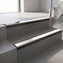 Satin Black aluminium stair nosing fitted along two concrete steps in an office stairwell, with a White anti-slip insert running the full width of each step