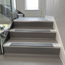 Square-edge aluminium stair nosing installed on a vinyl-covered office staircase, Mid Grey anti-slip insert, viewed up the flight
