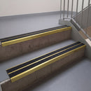 Square edge with ramped back aluminium stair nosing, 93mm tread, twin coal (black) exterior grip inserts, mirrorflect gold finish