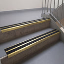 Square edge with ramped back aluminium stair nosing, 93mm tread, twin coal (black) exterior grip inserts, satin gold finish