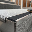 Rakeback aluminium stair nosing with midnight grey anti-slip insert on a pale carpeted school step