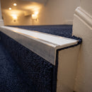 Rakeback aluminium stair nosing with white anti-slip insert on a dark carpeted hotel step