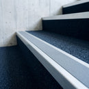 Close view of an aluminium stair nosing with a dolphin grey anti-slip insert on a navy carpeted library staircase