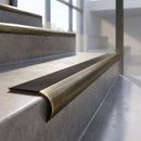 Antique Brass finish - solid brass raked back stair nosing with black anti-slip insert fitted on concrete steps