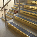 Polished Brass finish with Nimbus Castellated insert - 59.5mm solid brass raked front single channel stair nosing fitted to a stone step