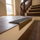 Solid brass stair nosing 59mm raked back slimline in antique brass finish with black castellated anti-slip insert, fitted to a stair tread