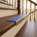 Solid brass stair nosing 59mm raked back slimline in antique brass finish with mid blue castellated anti-slip insert, fitted to a stair tread