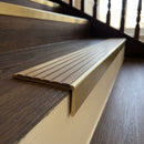 Solid brass stair nosing 59mm raked back slimline in antique brass finish with olive castellated anti-slip insert, fitted to a stair tread