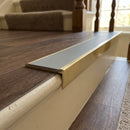 Solid brass stair nosing 59mm raked back slimline in antique brass finish with polar grey smooth textured anti-slip insert, fitted to a stair tread