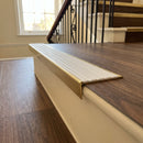 Solid brass stair nosing 59mm raked back slimline in antique brass finish with white castellated anti-slip insert, fitted to a stair tread
