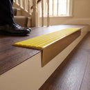 Solid brass stair nosing 59mm raked back slimline in antique brass finish with yellow castellated anti-slip insert, fitted to a stair tread