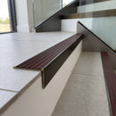 Solid brass stair nosing 59mm raked back slimline in antique bronze finish with claret castellated anti-slip insert, fitted to a stair tread