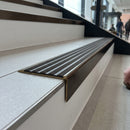 Solid brass stair nosing 59mm raked back slimline in antique bronze finish with granite castellated anti-slip insert, fitted to a stair tread