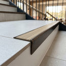 Solid brass stair nosing 59mm raked back slimline in antique bronze finish with ivory castellated anti-slip insert, fitted to a stair tread