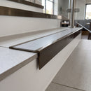 Solid brass stair nosing 59mm raked back slimline in antique bronze finish with light grey smooth textured anti-slip insert, fitted to a stair tread