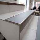 Solid brass stair nosing 59mm raked back slimline in antique bronze finish with polar grey smooth textured anti-slip insert, fitted to a stair tread