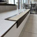 Solid brass stair nosing 59mm raked back slimline in antique bronze finish with porth stone castellated anti-slip insert, fitted to a stair tread