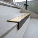 Solid brass stair nosing 59mm raked back slimline in antique bronze finish with satin brass anti-slip insert, fitted to a stair tread